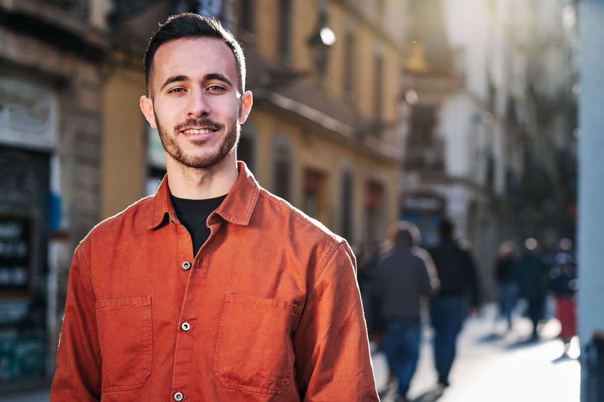 A man standing thoughtfully outdoors in soft afternoon light.