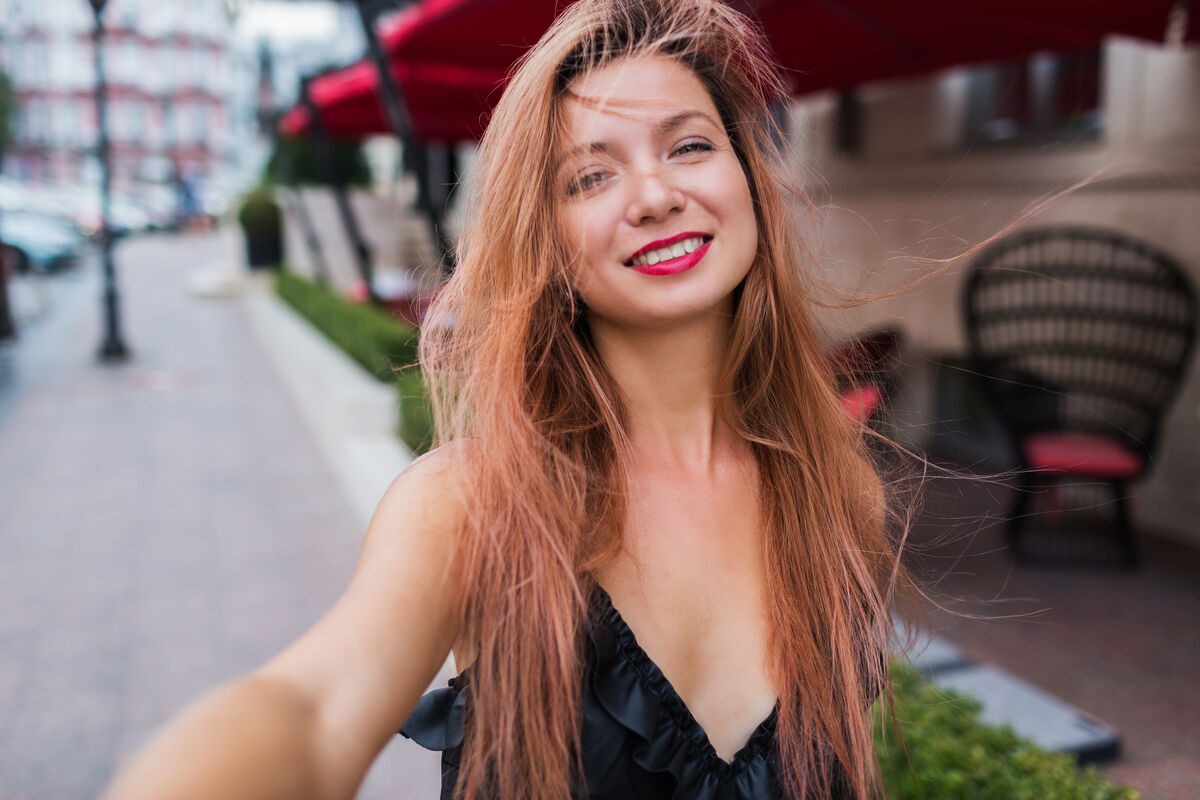 A young woman smiling warmly in soft daylight.